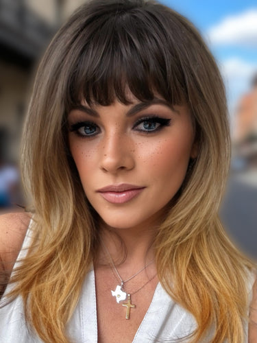 Close-up of a person with long, wavy hair wearing a white top and gold necklace.
